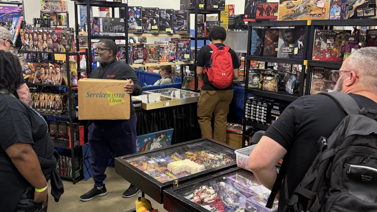 Collectors browsing densely packed vendor shelves of toys and collectibles on the Dominion Toy Con show floor